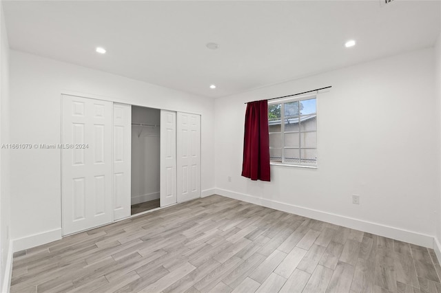 unfurnished bedroom with light wood-type flooring and a closet