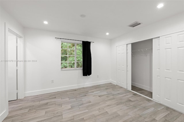 unfurnished bedroom with light wood-type flooring and a closet