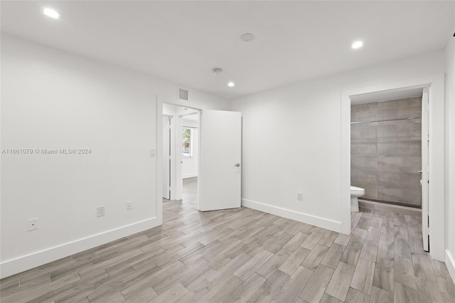 unfurnished bedroom featuring ensuite bathroom and light hardwood / wood-style floors