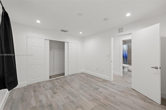 unfurnished bedroom with a closet, light hardwood / wood-style floors, and connected bathroom