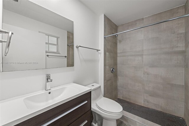 bathroom with a tile shower, vanity, and toilet