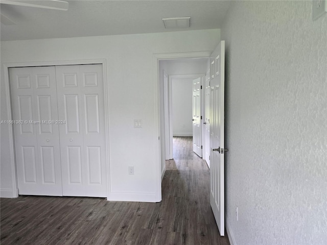 unfurnished bedroom with a closet, ceiling fan, and dark hardwood / wood-style flooring