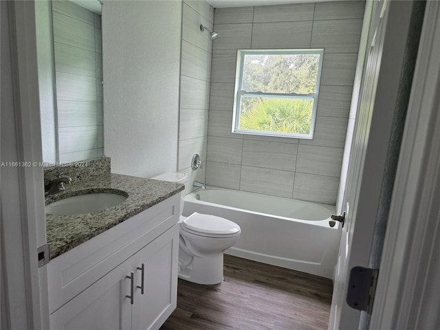 full bathroom featuring tiled shower / bath, vanity, hardwood / wood-style floors, and toilet