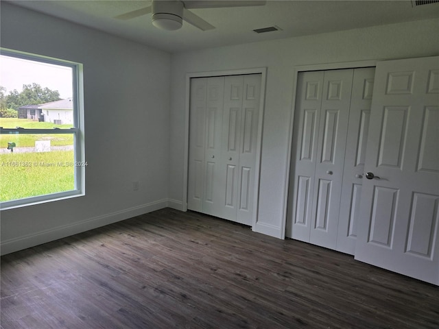 unfurnished bedroom with multiple closets, ceiling fan, and dark hardwood / wood-style flooring