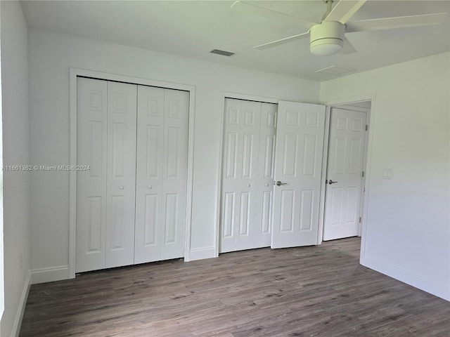 unfurnished bedroom with multiple closets, ceiling fan, and hardwood / wood-style flooring