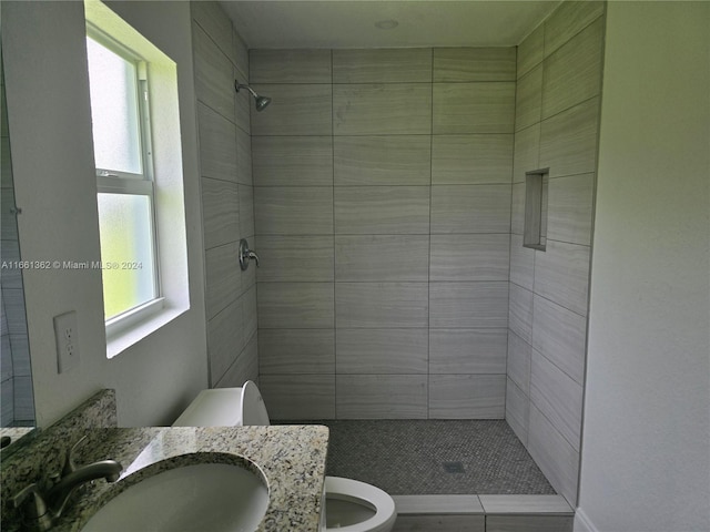 bathroom with a tile shower, plenty of natural light, and toilet