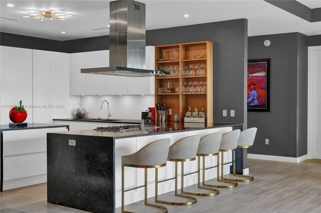 4701 N Meridian Ave Unit 510, Miami Beach, FL 33140 - kitchen featuring island exhaust hood, dark countertops, white cabinets, a sink, and open shelves