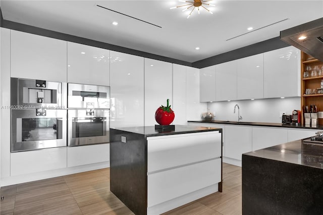 kitchen featuring white cabinets, stainless steel appliances, ventilation hood, a center island, and sink