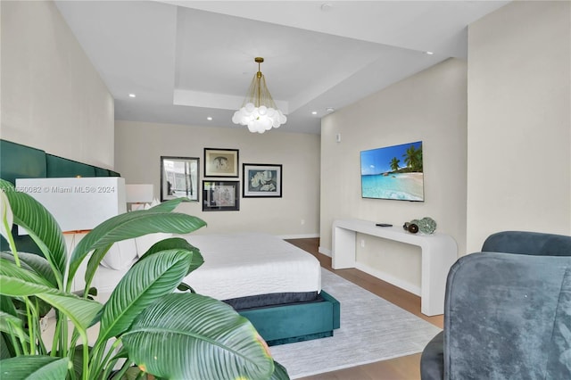 bedroom featuring hardwood / wood-style flooring, a tray ceiling, and a notable chandelier