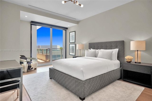 bedroom with a notable chandelier, light hardwood / wood-style floors, and access to exterior