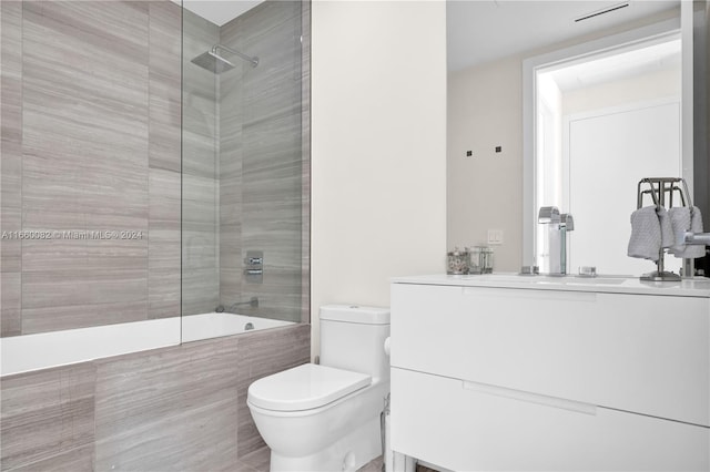 full bathroom featuring tiled shower / bath combo, vanity, and toilet