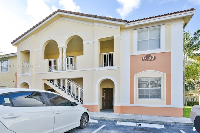 view of front of home featuring uncovered parking, stucco siding, and a tiled roof