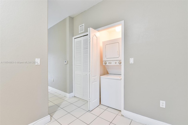 corridor featuring light tile patterned floors and stacked washing maching and dryer