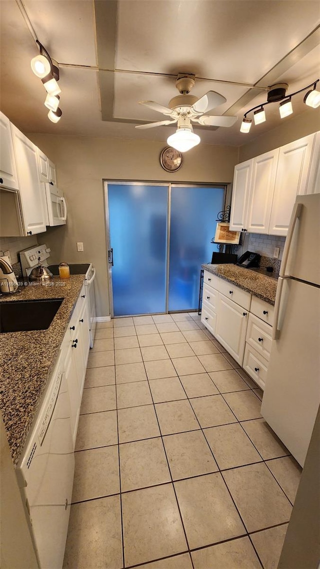 kitchen with light tile patterned floors, dark stone counters, white appliances, and white cabinetry