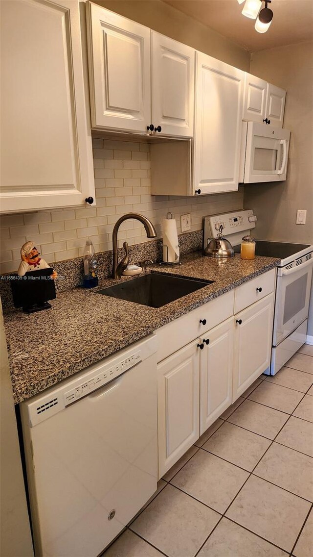 kitchen with light tile patterned flooring, white cabinetry, sink, and white appliances