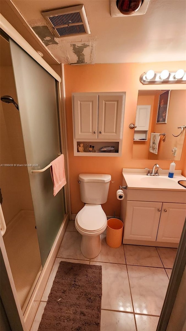 bathroom featuring toilet, tile patterned floors, vanity, and a shower with shower door