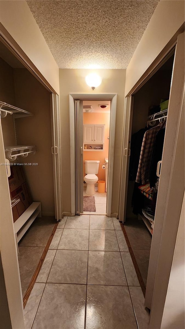 bathroom with a textured ceiling, tile patterned floors, and toilet