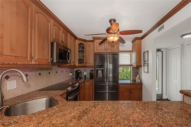 kitchen featuring appliances with stainless steel finishes, dark stone counters, sink, and ceiling fan