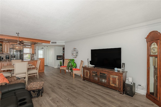 living room featuring ceiling fan, a textured ceiling, crown molding, and dark wood-type flooring