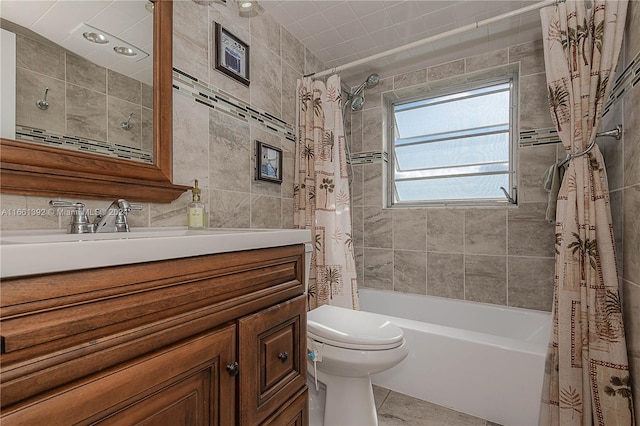 full bathroom with tile walls, tile patterned floors, shower / bath combo with shower curtain, vanity, and toilet