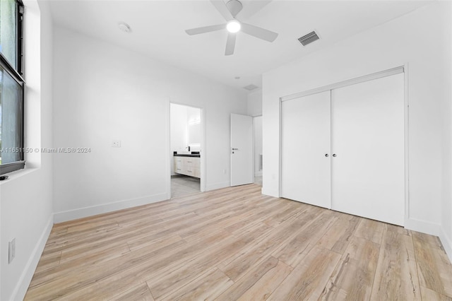 unfurnished bedroom featuring connected bathroom, light hardwood / wood-style floors, ceiling fan, and a closet