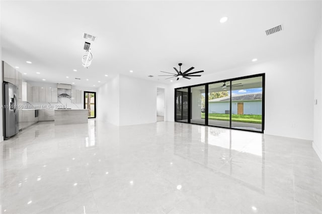 unfurnished living room featuring ceiling fan and plenty of natural light