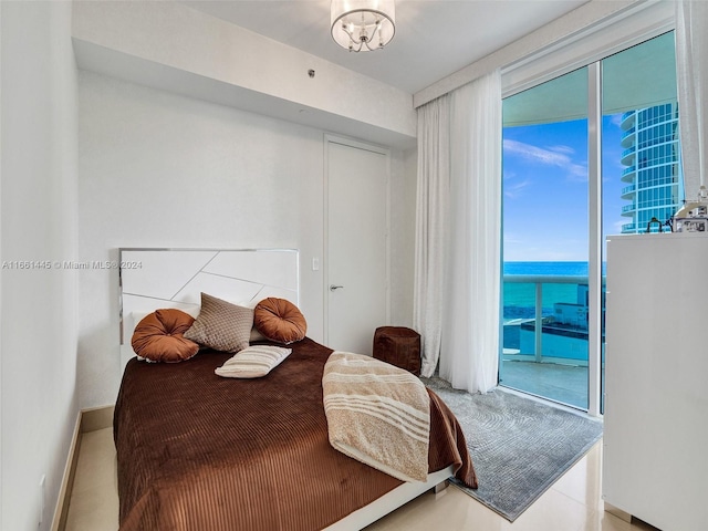 bedroom featuring access to outside, an inviting chandelier, and a water view