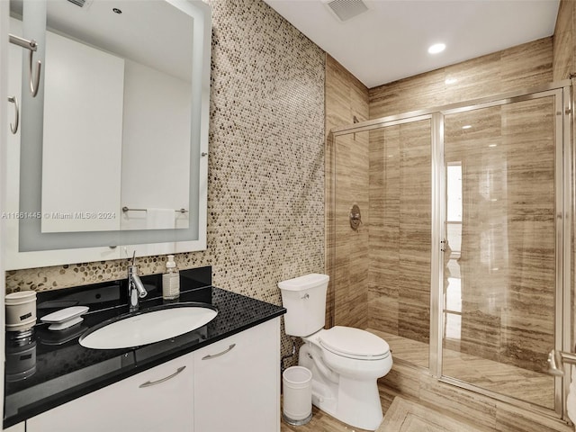 bathroom with tile walls, walk in shower, vanity, and toilet