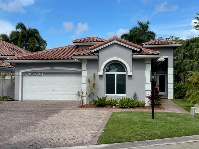 mediterranean / spanish-style house featuring a front yard and a garage