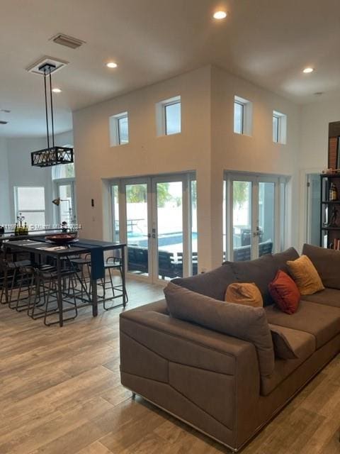 living room featuring a high ceiling, light hardwood / wood-style floors, and french doors