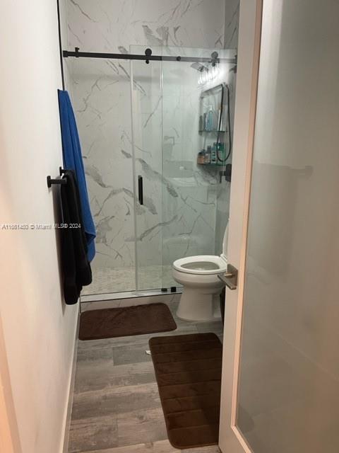 bathroom with walk in shower, toilet, and hardwood / wood-style flooring