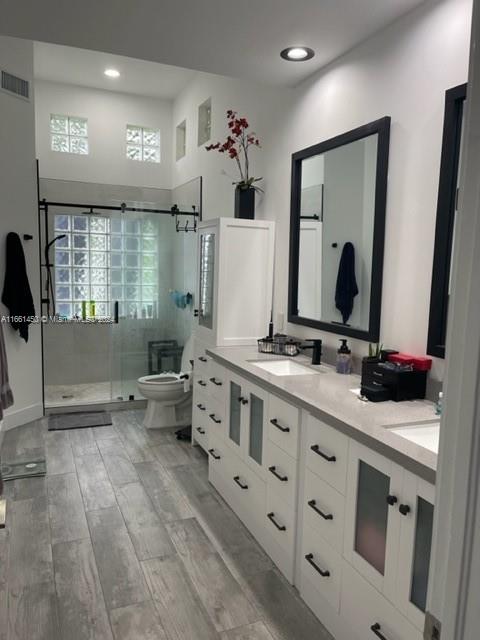 bathroom featuring wood-type flooring, walk in shower, vanity, and toilet