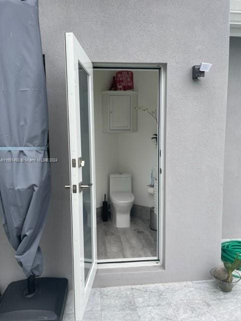 bathroom featuring walk in shower, hardwood / wood-style flooring, and toilet