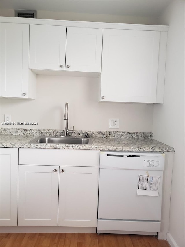 kitchen with hardwood / wood-style floors, sink, white dishwasher, and white cabinets