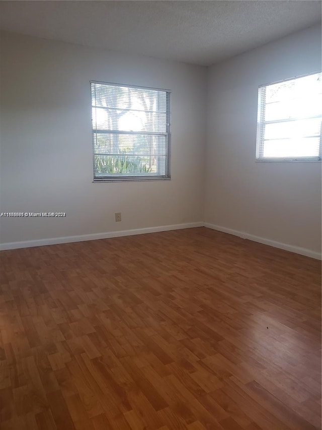 spare room with a textured ceiling and wood-type flooring