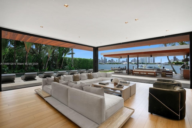 living room featuring floor to ceiling windows, light hardwood / wood-style floors, and a water view