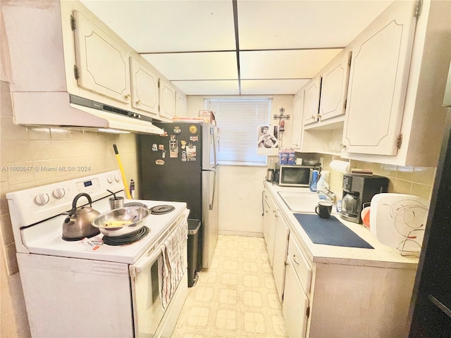 kitchen with white electric stove, decorative backsplash, sink, and white cabinets