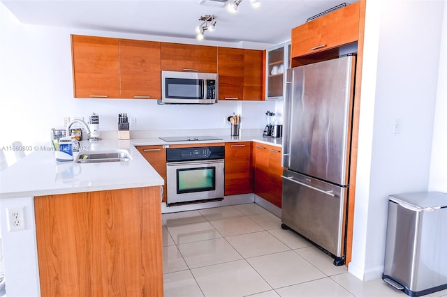 kitchen featuring kitchen peninsula, appliances with stainless steel finishes, light tile patterned floors, and sink