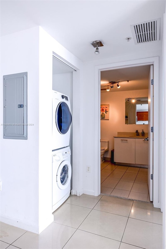 laundry room with stacked washer / drying machine, light tile patterned flooring, and electric panel