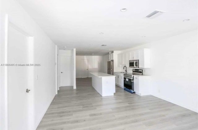 kitchen featuring a center island, sink, white cabinets, light hardwood / wood-style flooring, and appliances with stainless steel finishes