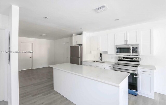 kitchen featuring a kitchen island, sink, stainless steel appliances, and white cabinets