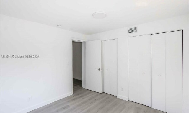 unfurnished bedroom featuring two closets and light hardwood / wood-style floors