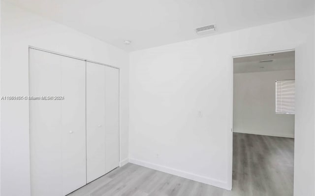 unfurnished bedroom with light hardwood / wood-style flooring and a closet