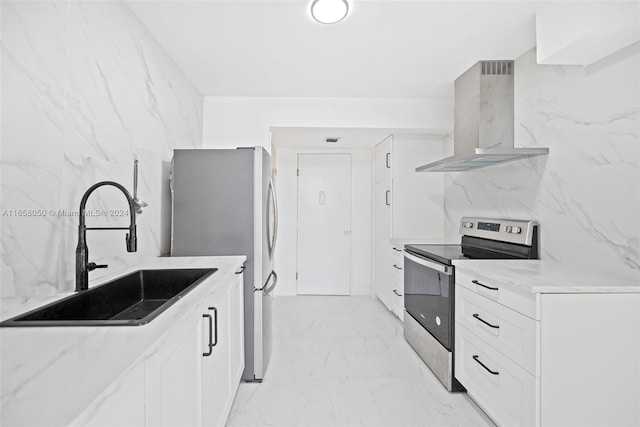 kitchen featuring white cabinetry, wall chimney exhaust hood, light stone countertops, stainless steel appliances, and sink