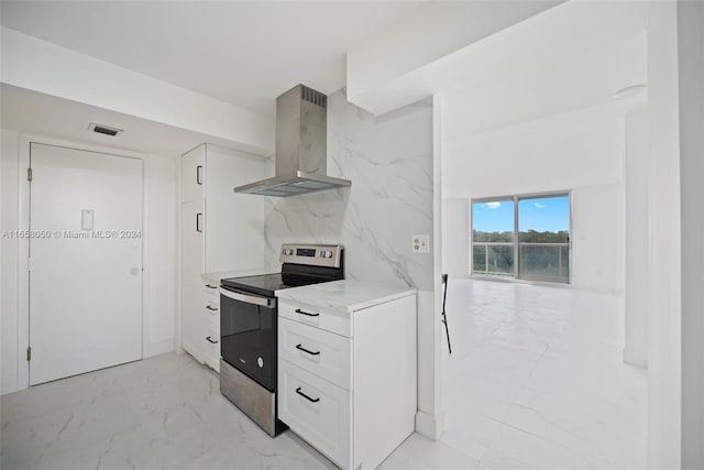 kitchen with backsplash, stainless steel electric stove, wall chimney range hood, and white cabinets