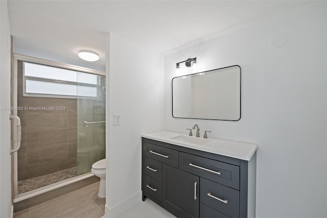 bathroom with a tile shower, tile patterned flooring, vanity, and toilet