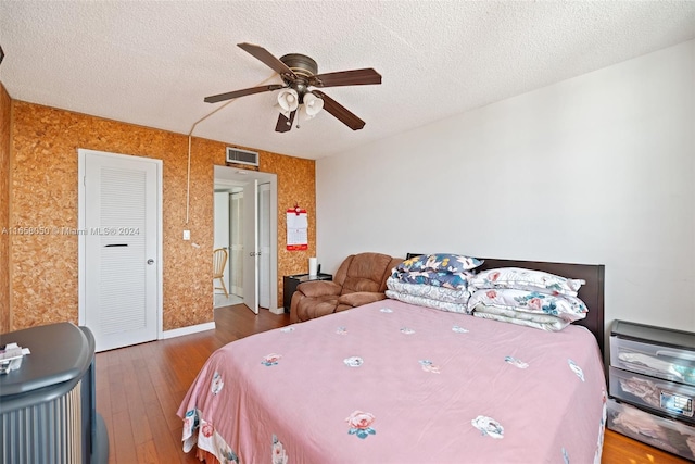 bedroom with ceiling fan, a textured ceiling, and wood-type flooring