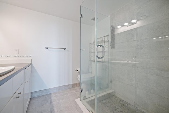 bathroom featuring vanity, a shower with shower door, toilet, and tile patterned flooring