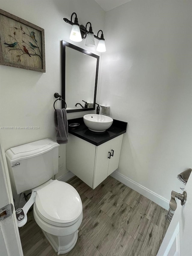 bathroom with wood-type flooring, vanity, and toilet