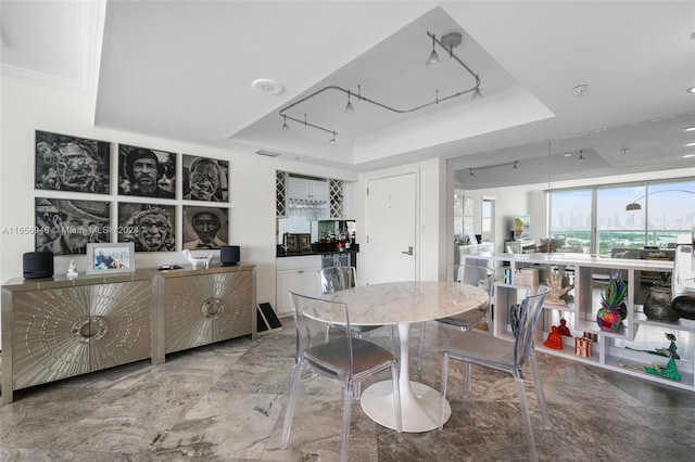 dining area with a tray ceiling and crown molding